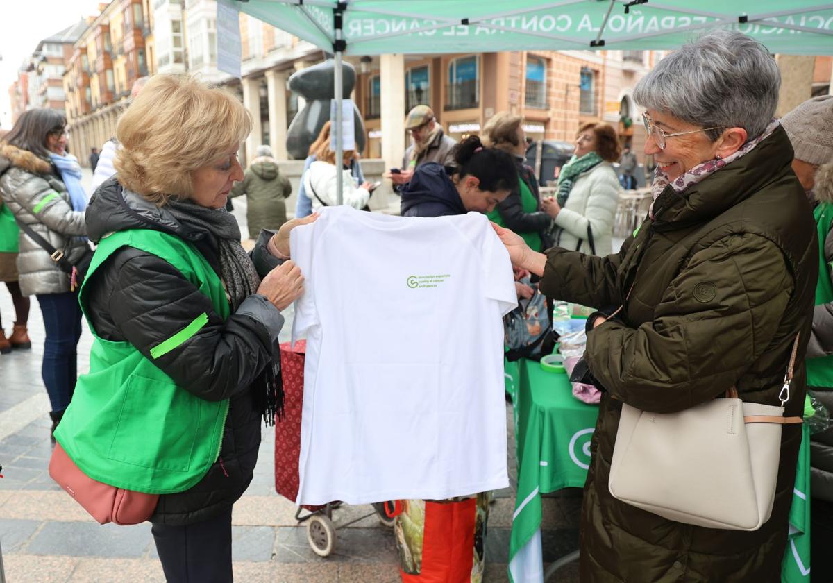 Dos voluntarias ojean una camiseta entre los artículos puestos a la venta para recaudar fondos.