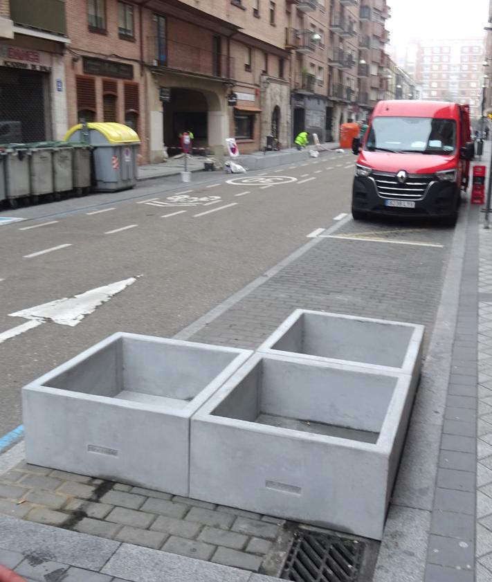 Imagen secundaria 2 - Arriba, cartel y maceteros colocados en el acceso al pasadizo desde la plaza de Federico Watenberg. Debajo, a la izquierda, bancos de madera recién instalados sobre los antiguos bloques de piedra frente al Colegio de Abogados, A la derecha, maceteros frente al bar La Tartana.