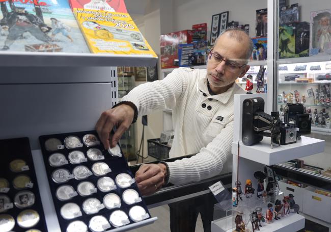 Francisco Javier Rebollo coloca monedas en el escaparate de su tienda