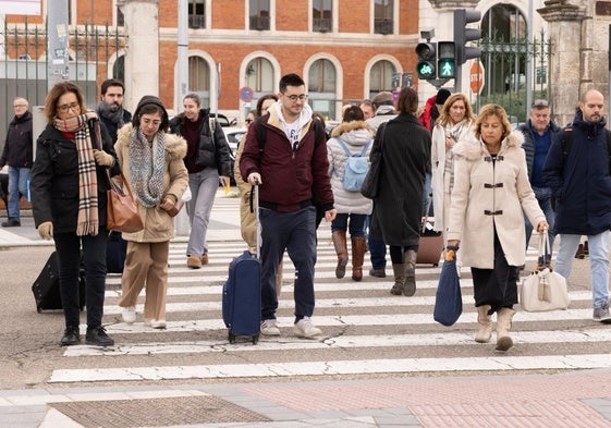 Viajeros cruzan un paso cebra con sus maletas.