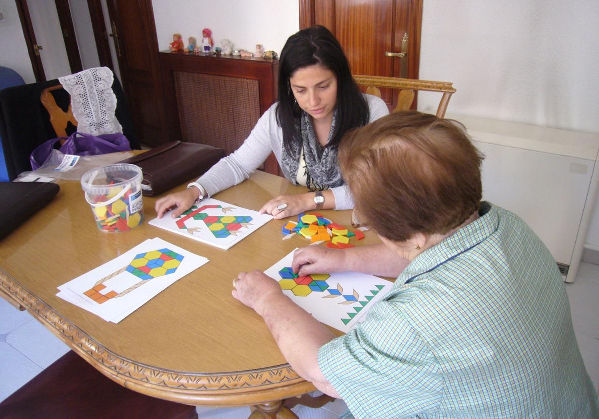 Una mujer practica ejercicios de agilidad mental con la profesional de ayuda a domicilio.