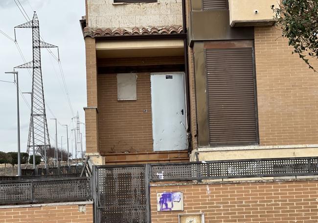 Puerta antiokupas en un chalé, con el tendido eléctrico de fondo que imposibilita que se habiten las viviendas.