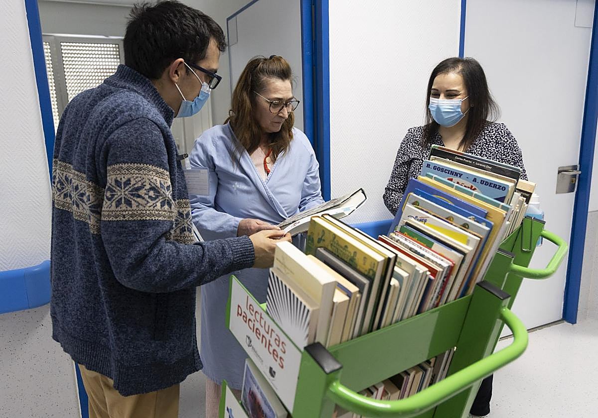 Dos voluntarios de Cadena de Sonrisas y la paciente Felisa Tesedo escoge un libro de lectura