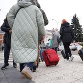 Varias personas con maletas, camino de la estación de ferrocarril.