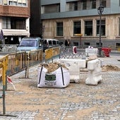 Dos vehículos circulan por la plaza, cuyo centro sigue a la espera del mobiliario urbano.