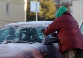 Un hombre retira el hielo de la luna de su coche.