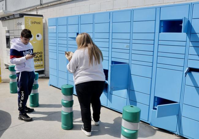 Dos jóvenes extraen sus paquetes de un 'locker' de Amazon instalado junto a otro de InPost en una gasolinera de Valladolid.