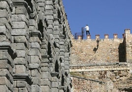 Un hombre subido en la zona de la muralla junto a la verja del Postigo que impide el paso a la parte alta del Acueducto.