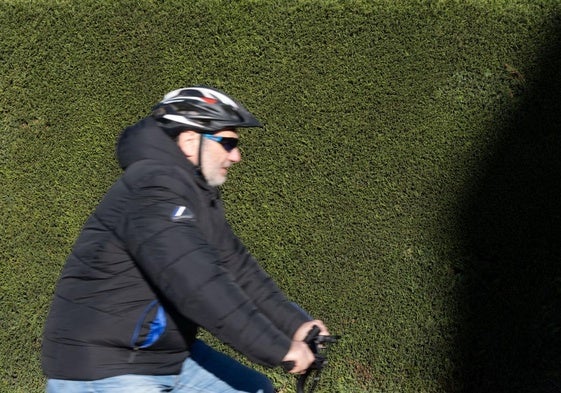 Un ciclista pasa delante de un seto tupido de plantas crupesáceas.