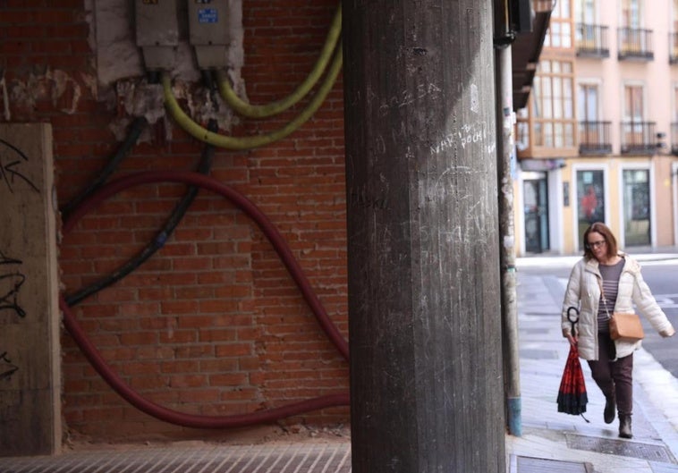 Una viandante atraviesa la acera de la calle Pedro Barruecos a la altura del muro que divide los soportales.
