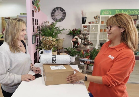 La florista María Martínez, a la izquierda, junto a una de las trabajadoras de Seur que le llevan y recogen los paquetes.