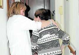Una auxiliar ayuda a una anciana.