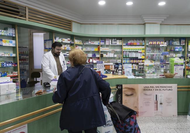 Héctor Crespo atiende a una clienta en la farmacia de la avenida de Segovia.