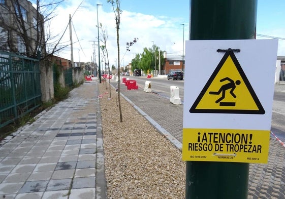 Una llamativa señal advierte a los peatones del riesgo de caídas en la acera adoquinada, pero aún en obras, de la avenida de El Norte de Castilla.