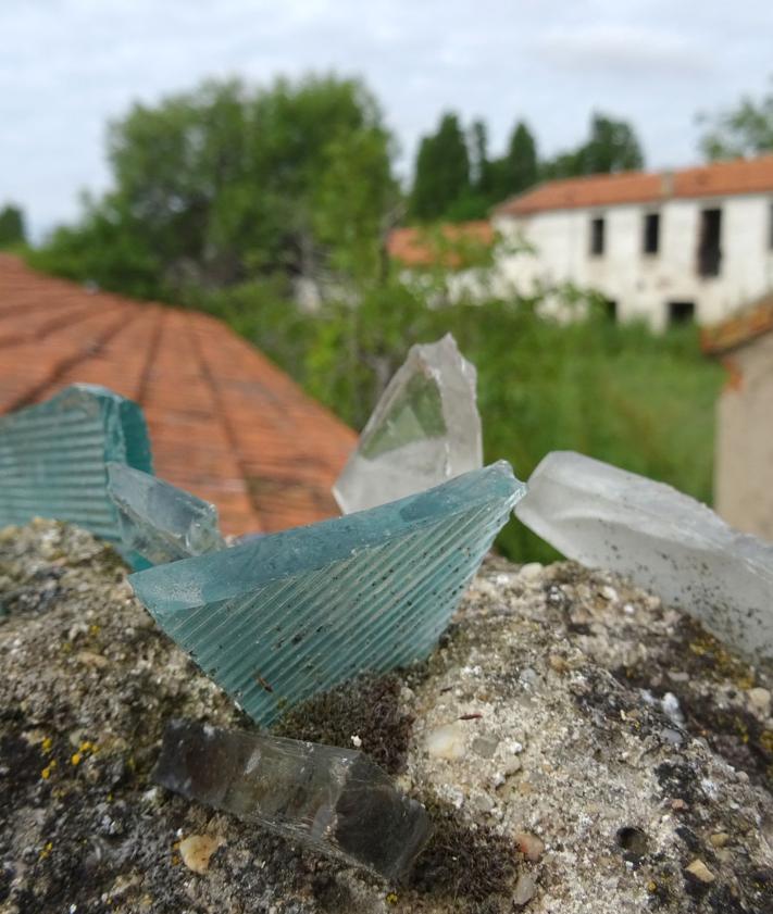 Imagen secundaria 2 - Arriba, edificaciones demolidas y en mal estado en el interior de la antigua explotación. Debajo, a la izquierda, detalle del rótulo en una esquina de la Granja Luisa. A la derecha, cristales en los muros para evitar el acceso a la parcela municipal