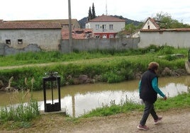 Una mujer pasea por el camino del Canal del Duero que discurre por el lateral de la Granja Luisa, en el polígono de San Cristóbal, donde se asoma la casa ocupada en el terreno municipal desde hace seis años.