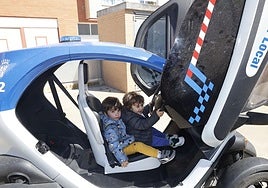 Dos niños disfrutan en uno de los coches de la Policía Local.