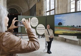 Una mujer toma una foto a Mari Martínez Ramos, autora del cuadro de Pino del Río junto al que posa.