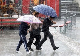 Tres personas intentan protegerse de la lluvia caída este miércoles en Segovia capital.