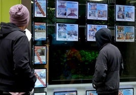 Dos hombres observan ofertas inmobiliarias en una agencia de la ciudad de Segovia.
