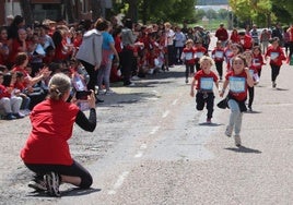 Un grupo de escolares participa en la carrera solidaria de Cuéllar bajo la atenta mirada de familiares, profesores y compañeros.