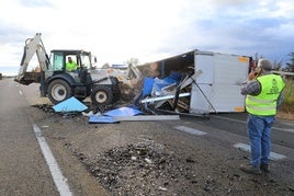 Una excavadora retira la carga del camión volcado en la carretera.
