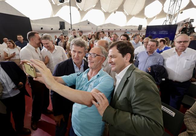 Un asistente al acto que el PP celebró este viernes en Valladolid se hace una foto con Feijóo y Mañueco.