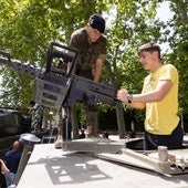 Un joven sujeta el póster de un tanque ante la mirada de un militar.