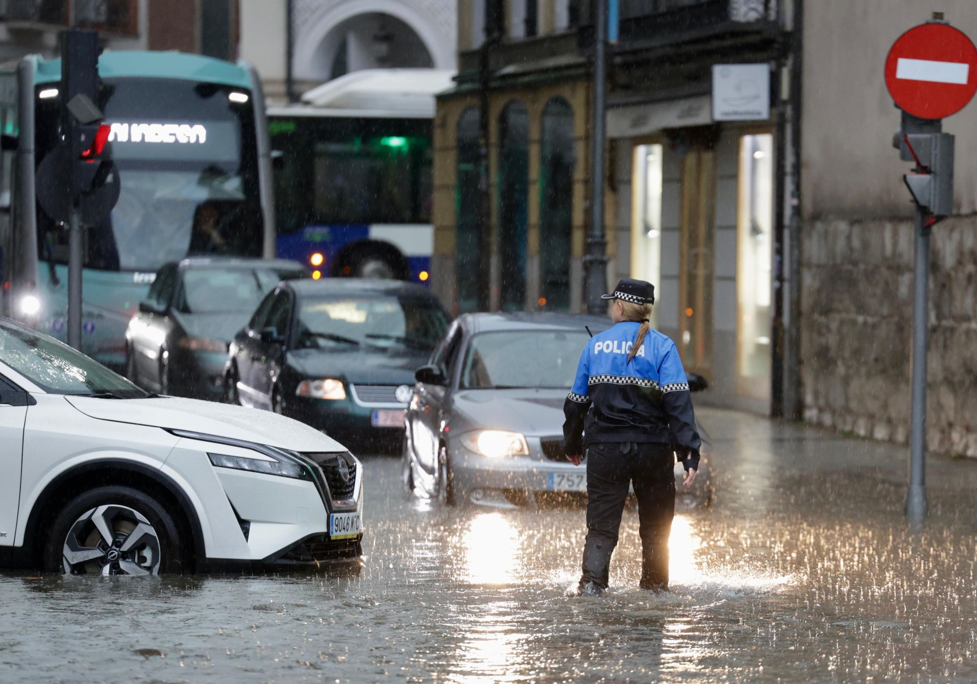 Una agente de la Policía Municipal de Valladolid regula el tráfico con el agua llegandole por encima del tobillo junto a la plaza de Portugalete.