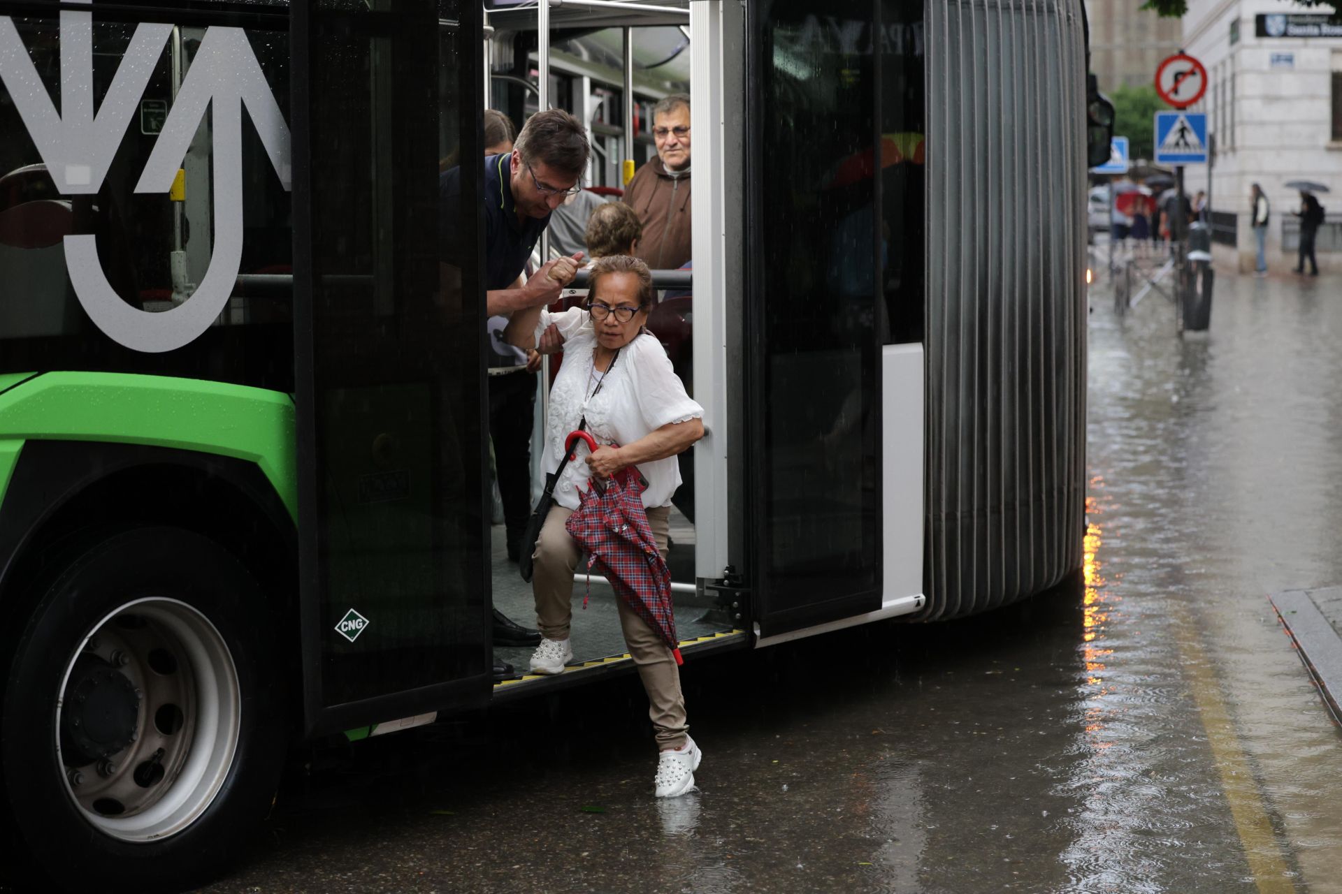 Una mujer es ayudada a bajar del autobús.