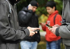 Adolescentes consultando sus teléfonos móviles.