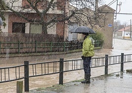 Un hombre junto a un arroyo crecido tras caer una troma de agua.
