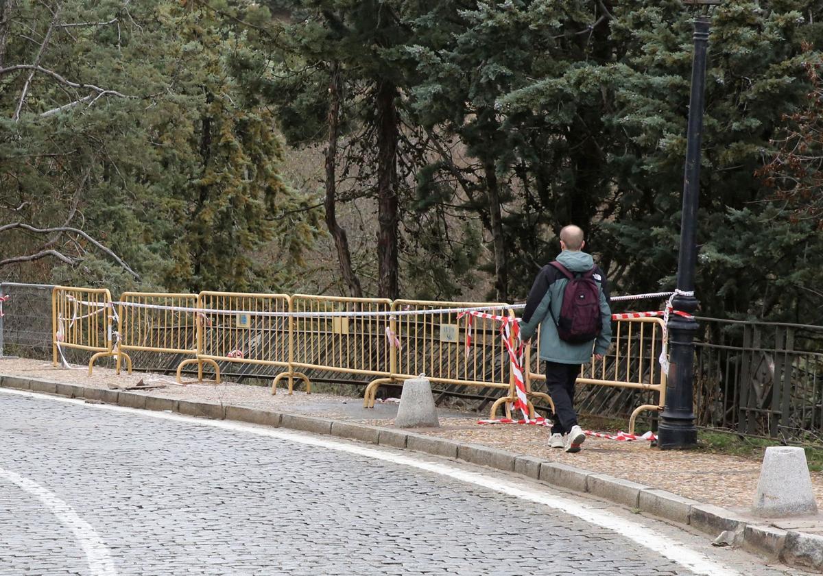 Un hombre pasa junto a un precinto tras un accidente en la Cuesta de los Hoyos.