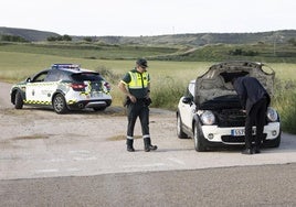 Un agente de la Guardia Civil inspecciona un coche tras colisionar con un corzo en Valoria la Buena este jueves.