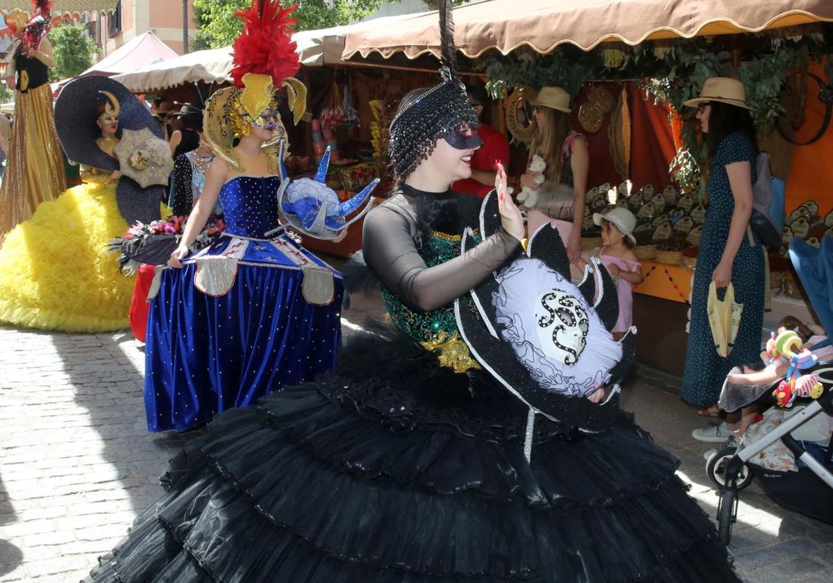 Participantes en el desfile saludan a los visitantes que recorren los puestos del Mercado Barroco de La Granja.