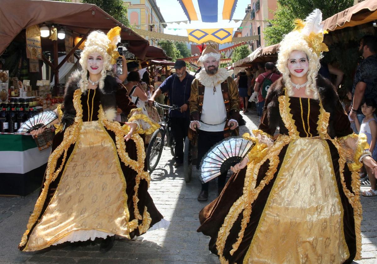 Imagen principal - Arriba, desfile de vestidos de época en el Mercado Barroco, abajo una exhibición de cetrería y a la derecha, unas niñas disfrazdas pasean por los puestos de artesanía. 