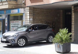 Un coche sale de un garaje comunitario en la calle Menéndez Pelayo, junto al que se anuncia la próxima apertura de trasteros.