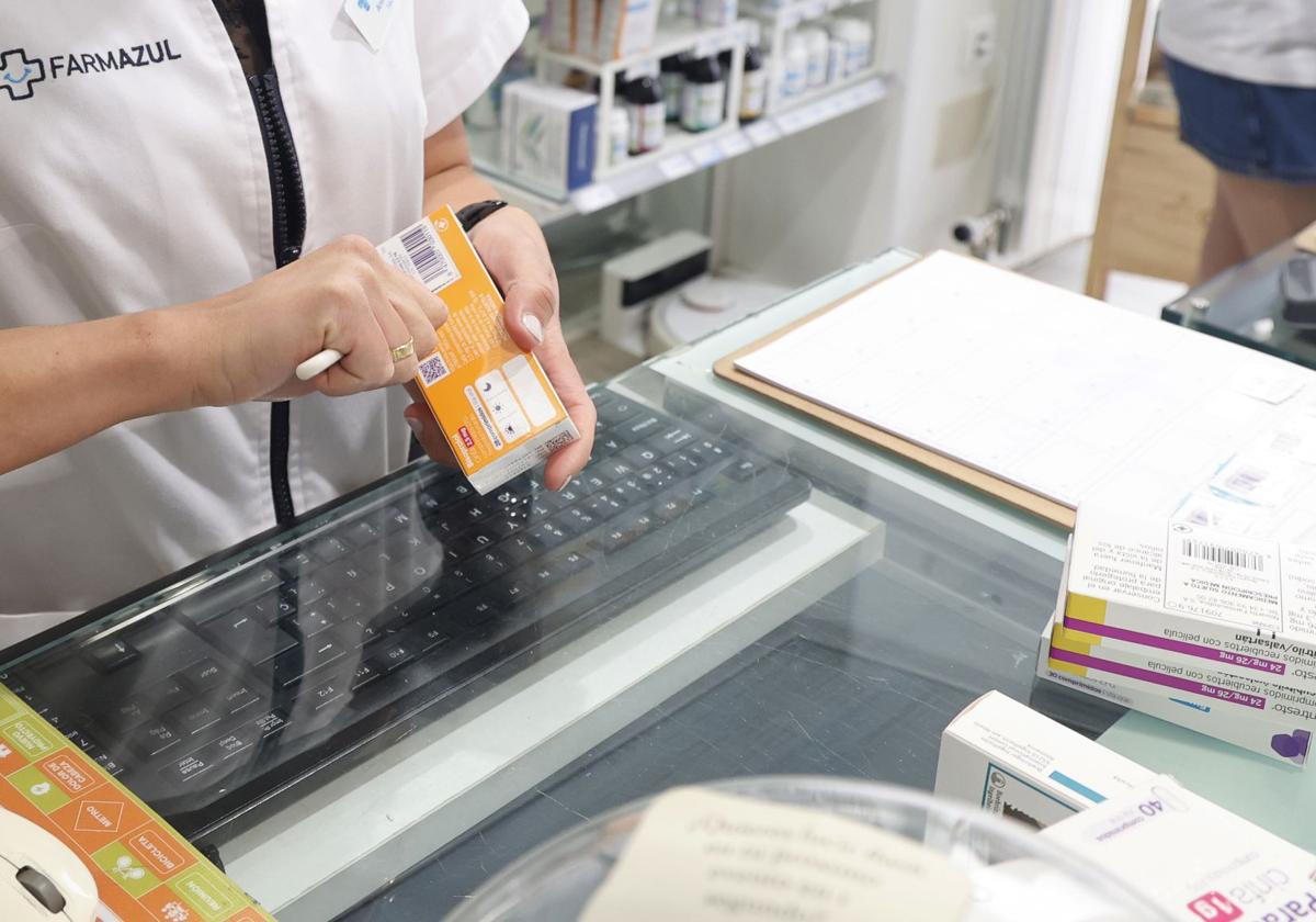 Una farmacéutica corta el código de barras de un medicamento.