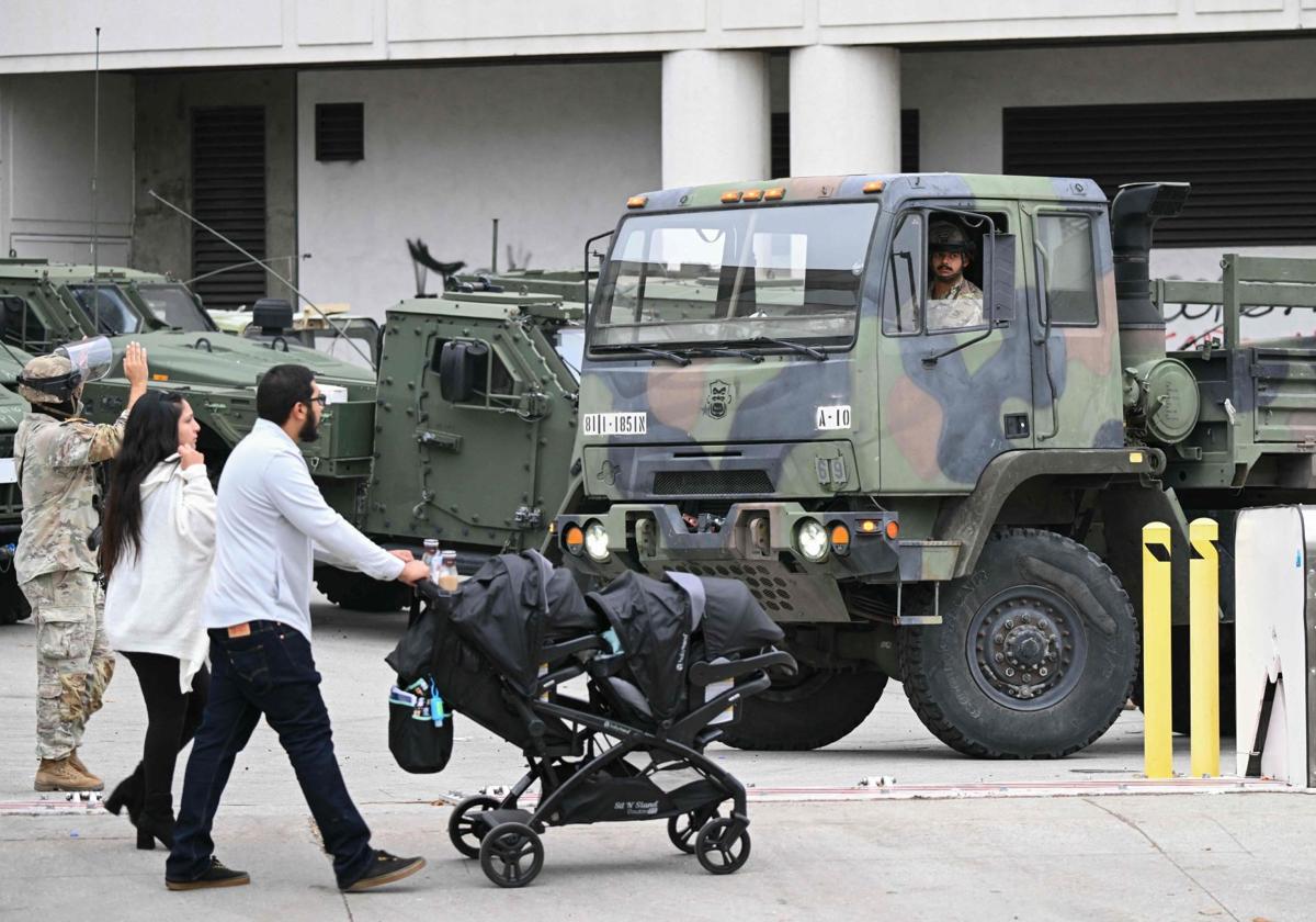 Una pareja pasea con sus hijos frente a miembros de la Guardia Nacional desplegados en Los Ángeles.