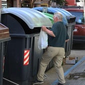Un vecino deposita una bolsa de basura en un contenedor.