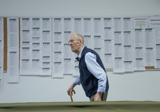 Una persona camina por delante de los listados provisionales con aceptados para los cursos de los centros de vida activa del Ayuntamiento.