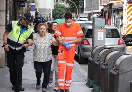 Los servicios de emergencia ayudan a una mujer a salir de la zona del incendio.