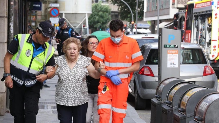 Los servicios de emergencia ayudan a una mujer a salir de la zona del incendio.