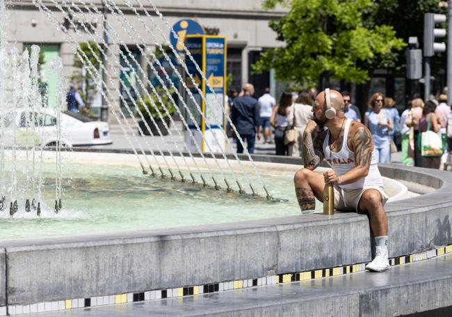 Un hombre se refresca en la fuente de la plaza de Zorrilla.