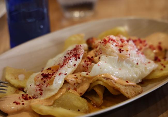 Plato 'los cojones del galán' de la taberna Pico Fino a base de huevos fritos con patatas, pulpo braseado y langostinos al ajillo.
