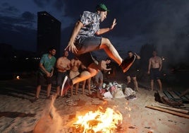 Un joven salta el fuego en la playa de las Moreras.