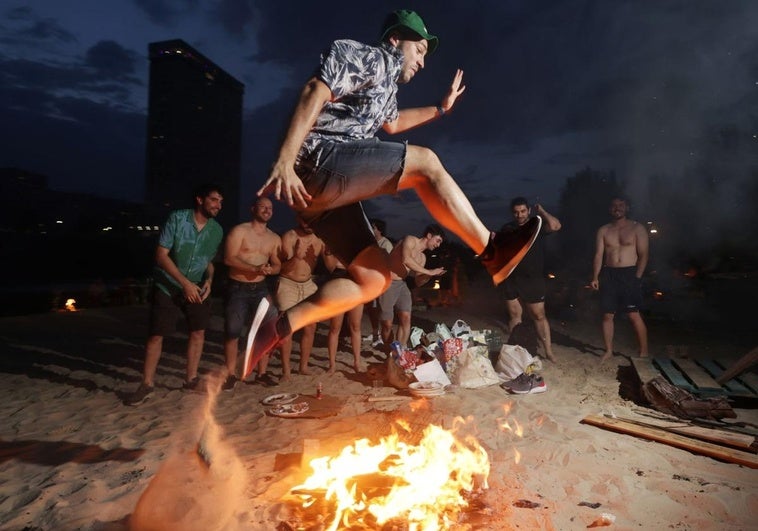Un joven salta el fuego en la playa de las Moreras.