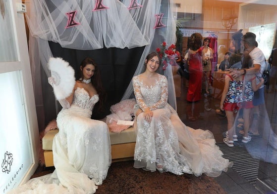 Dos jóvenes con vestidos de novia en un escaparate durante la Showpping Night.