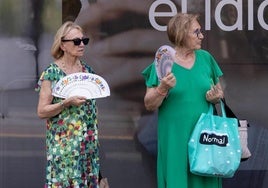 Dos mujeres combaten el calor con abanicos en la plaza de España.