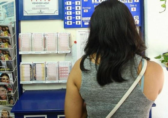 Una mujer elige uno de los boletos para participar en los sorteos de loterías.